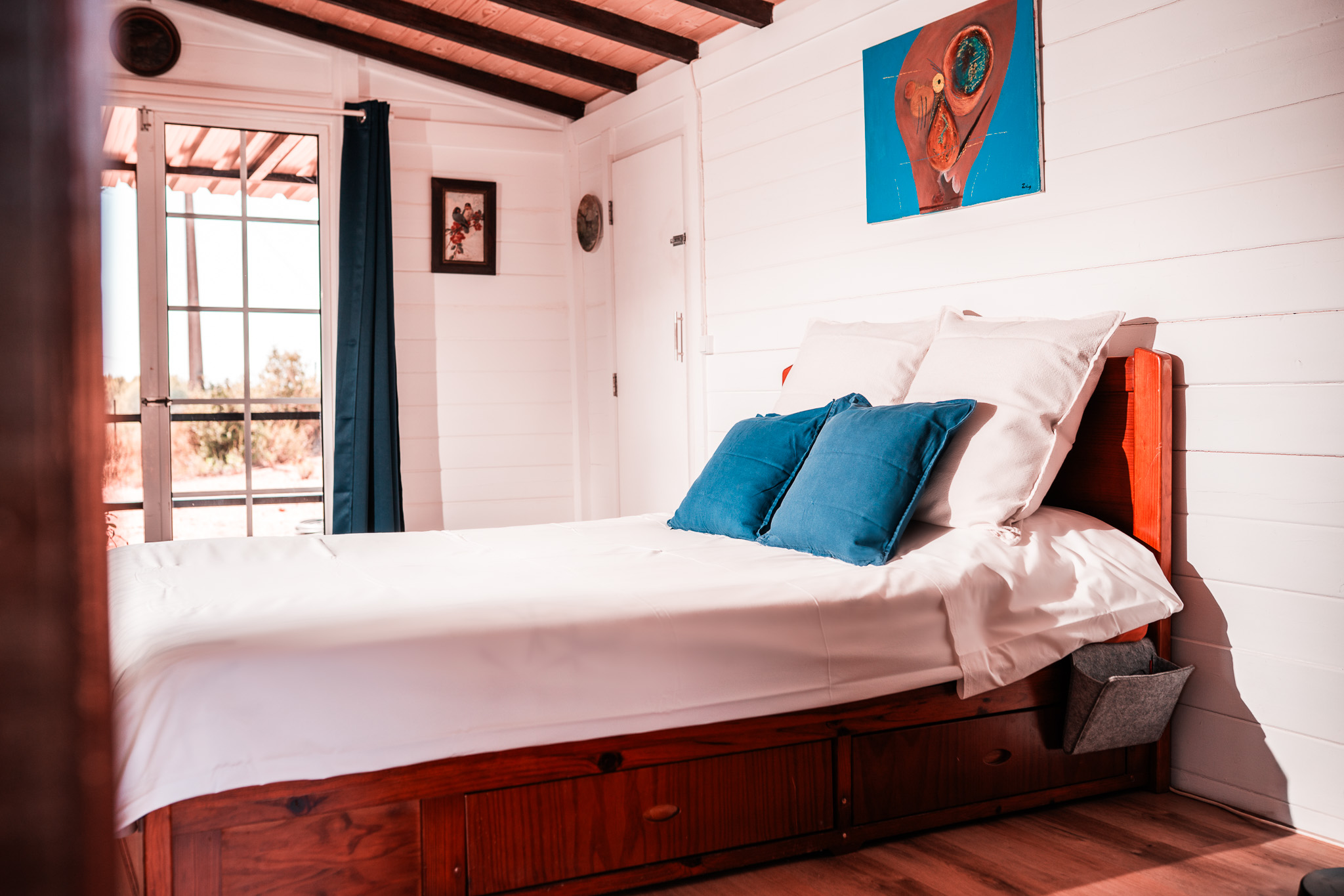 The Wooden Cabin — bedroom with double bed and blue cushions