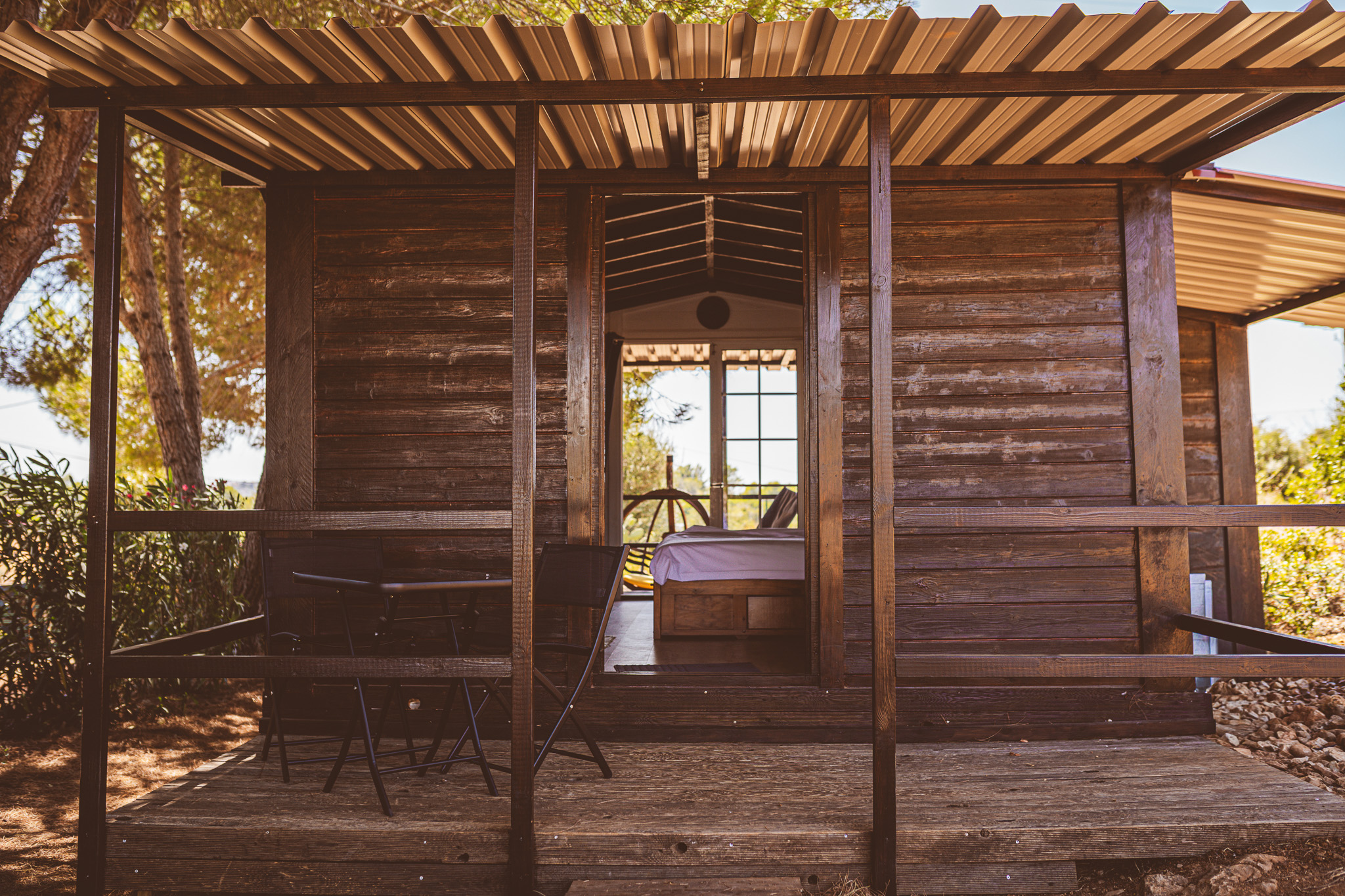 The Wooden Cabin — covered front terrace with the door open to the bedroom