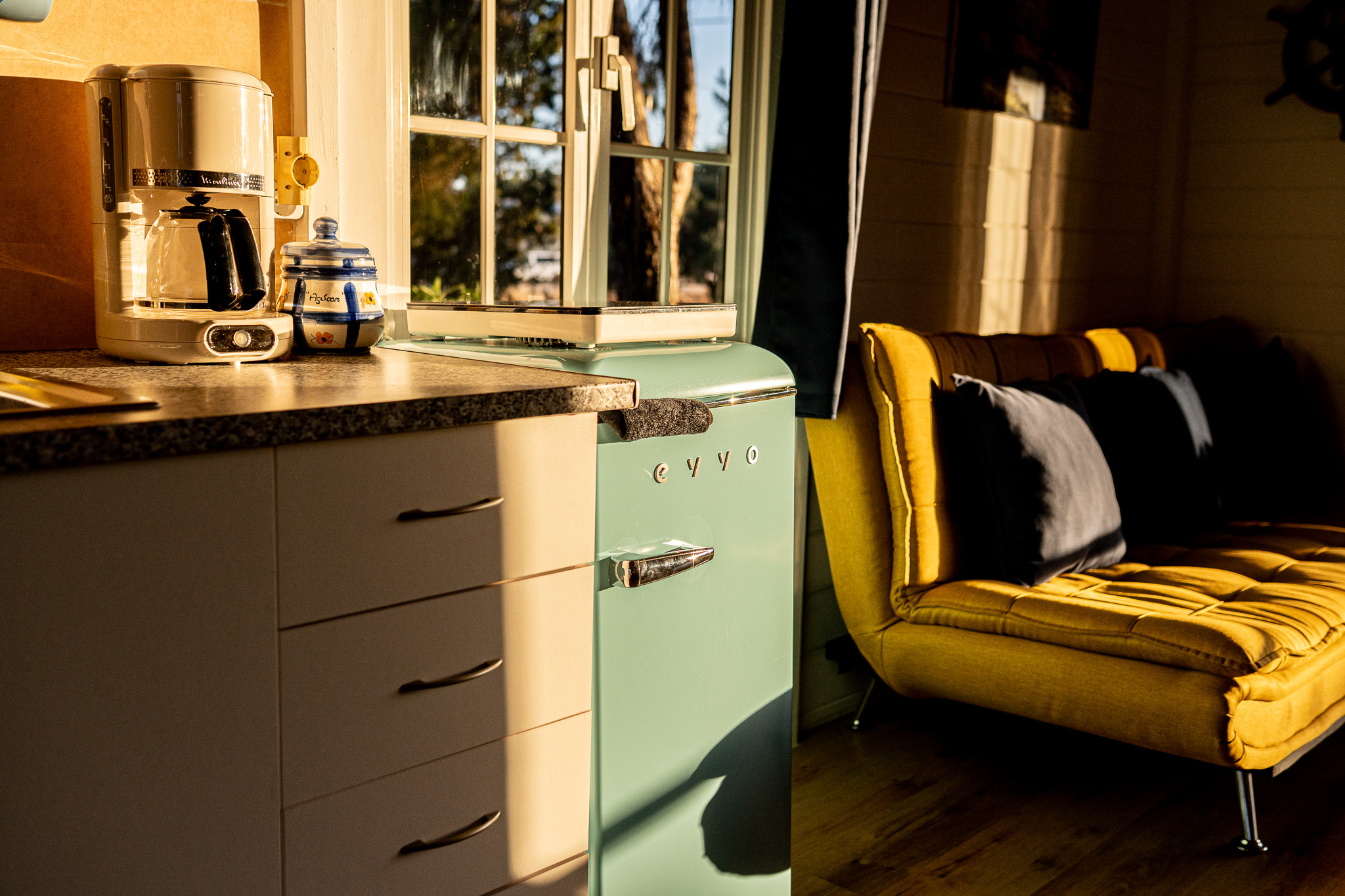 Cabin kitchenette with coffee maker, fridge and yellow sofa