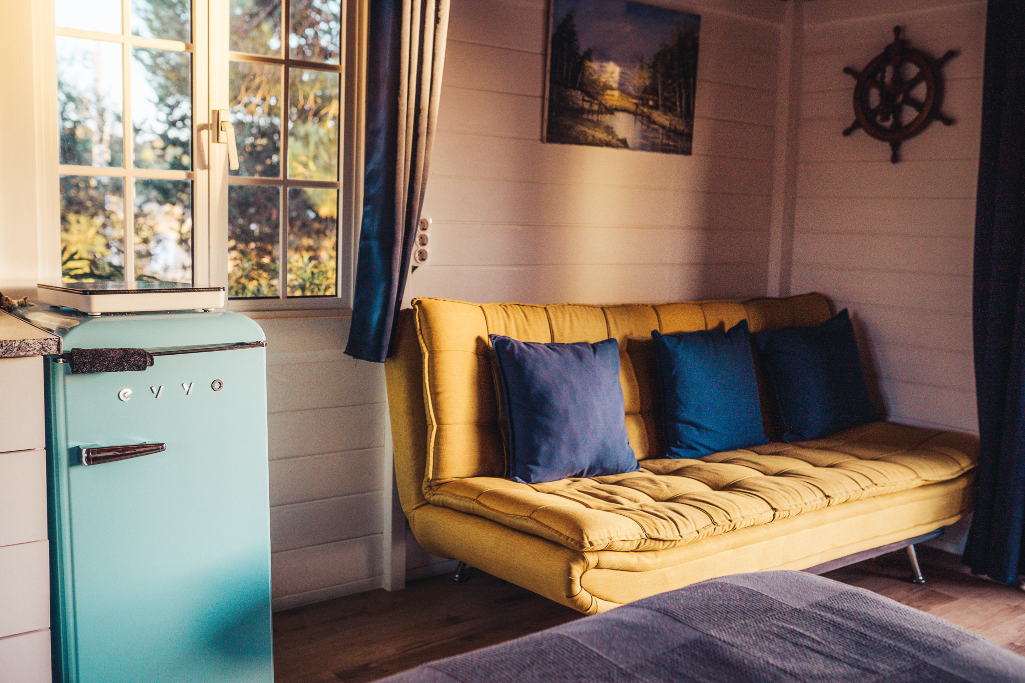 Cabin living area with yellow sofa and turquoise fridge