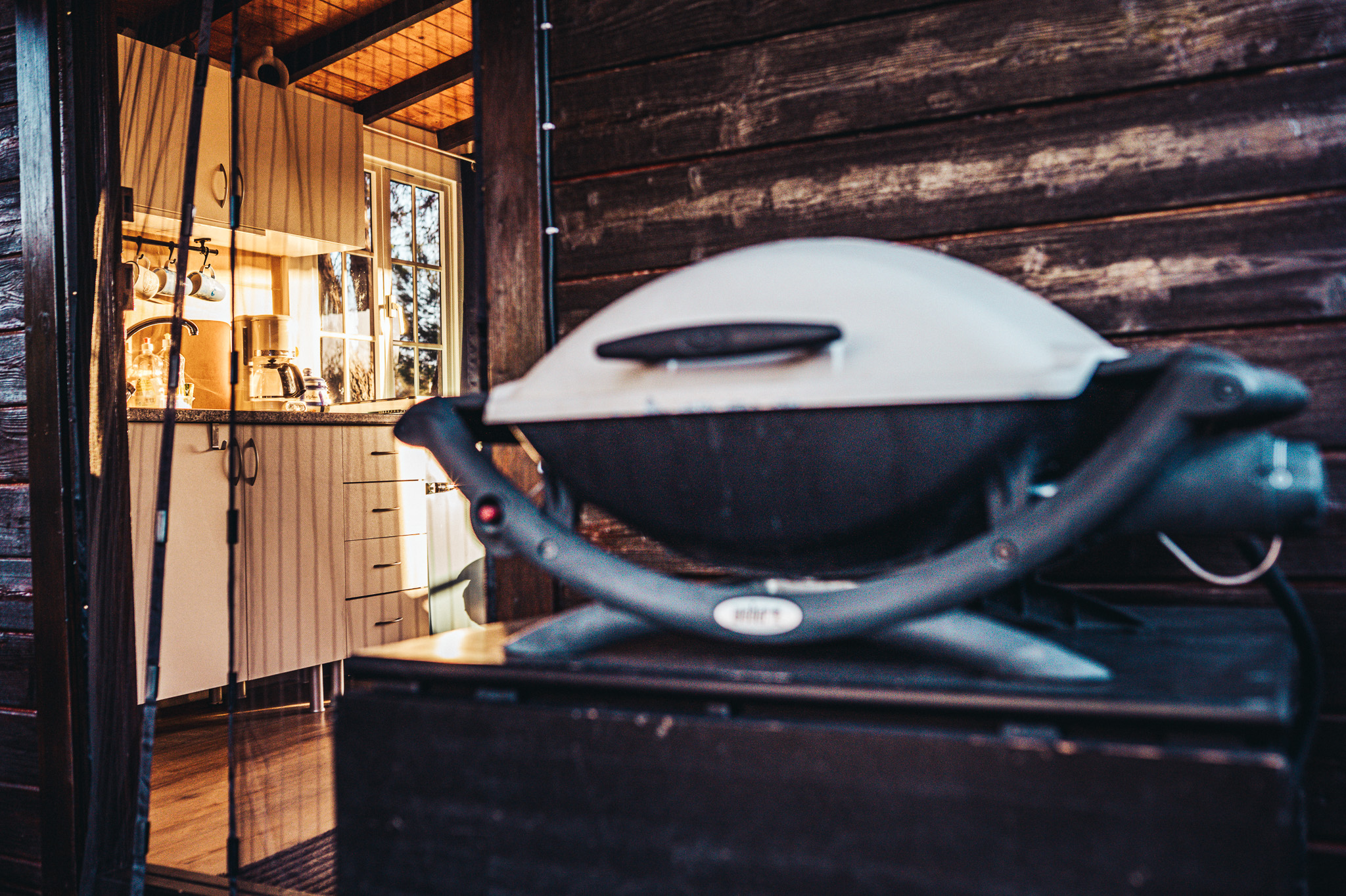 Grill on the cabin terrace with the kitchen behind